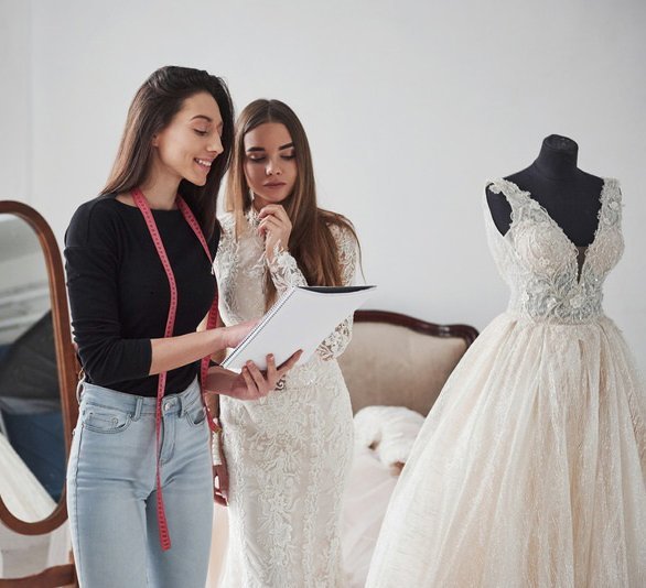 A women in wedding dresses assisted by John Emily Studio.