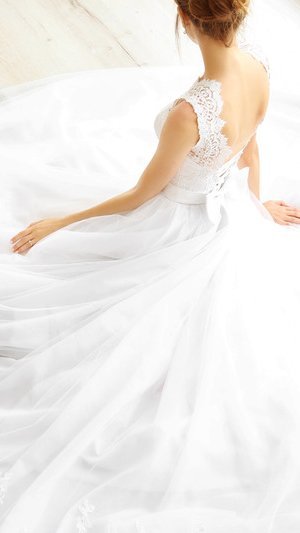 A bride in a white wedding gown sitting gracefully.