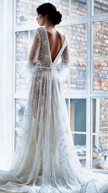 A bride in a wedding gown gazing out of a window.