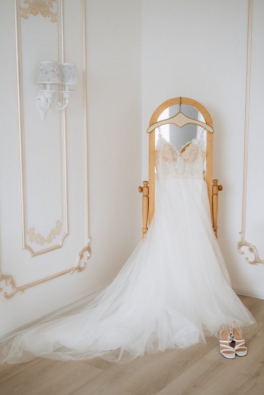 A white wedding dress hanging on a wall.