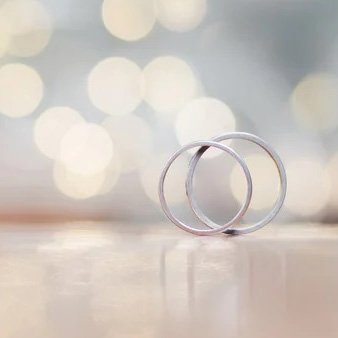 Two wedding rings on a table against a blurred background
