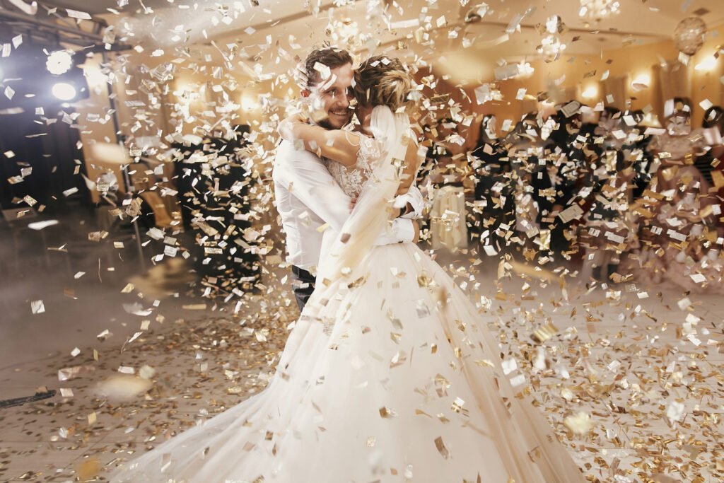 Newlyweds hugging surrounded by falling confetti.