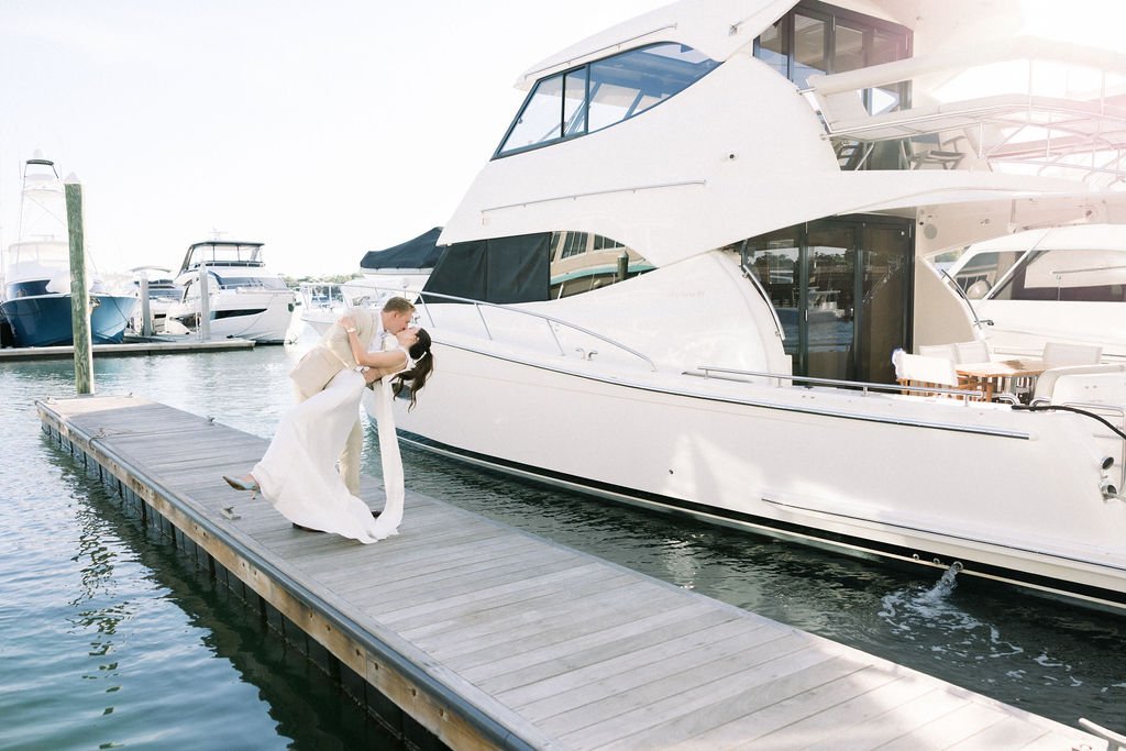Wedding couple embracing on a marina dock beside a yacht
